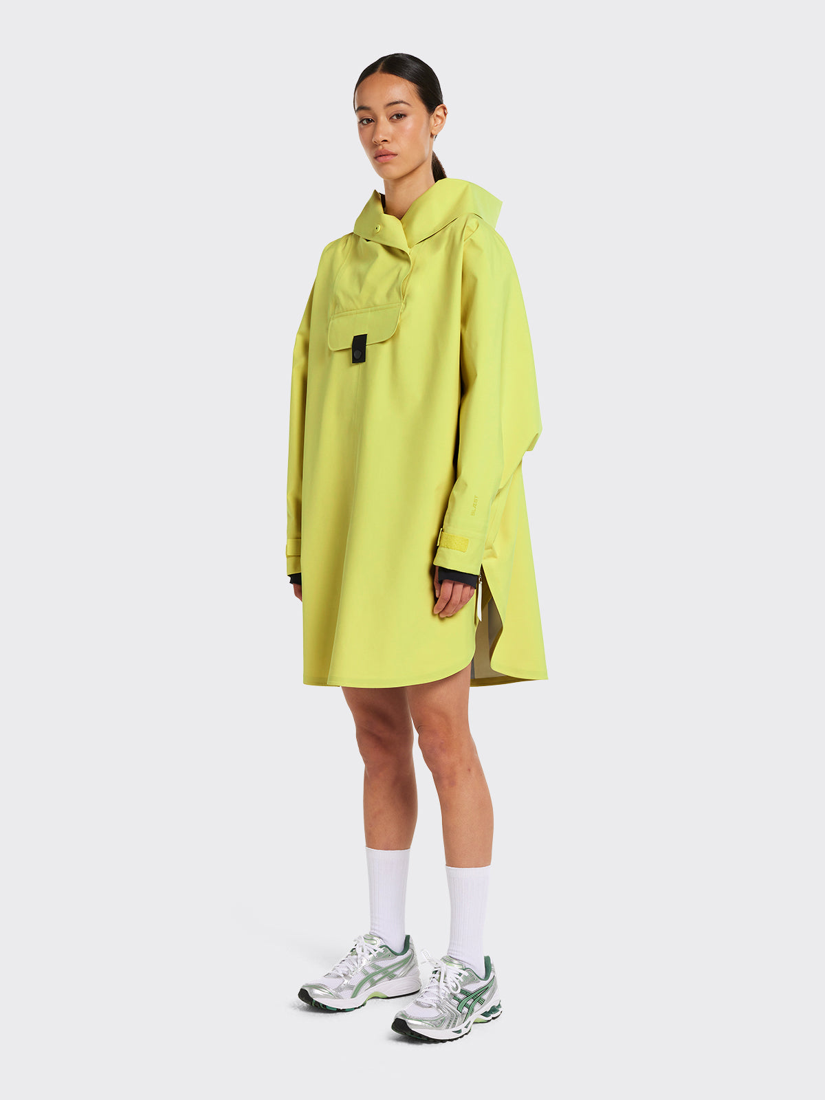 Woman wearing Bergen poncho in the color Muted Lime by Blæst